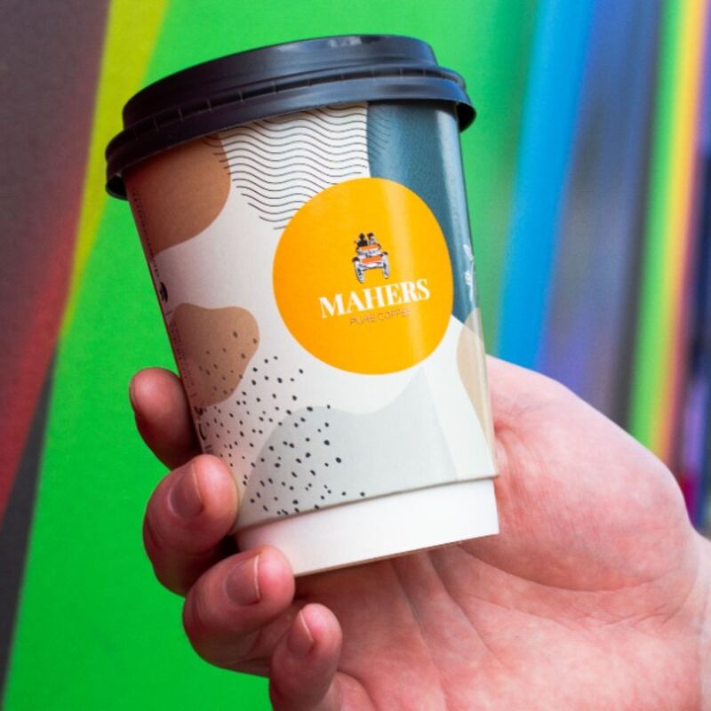 A Mahers takeaway cup held in a hand